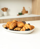 Mini stoneware serving platter with a selection of pastries and blackberries on a kitchen countertop.