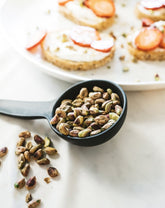 A stoneware bowl with a spoon shape, placed on a table with some food items, used as a serving dish for a meal.