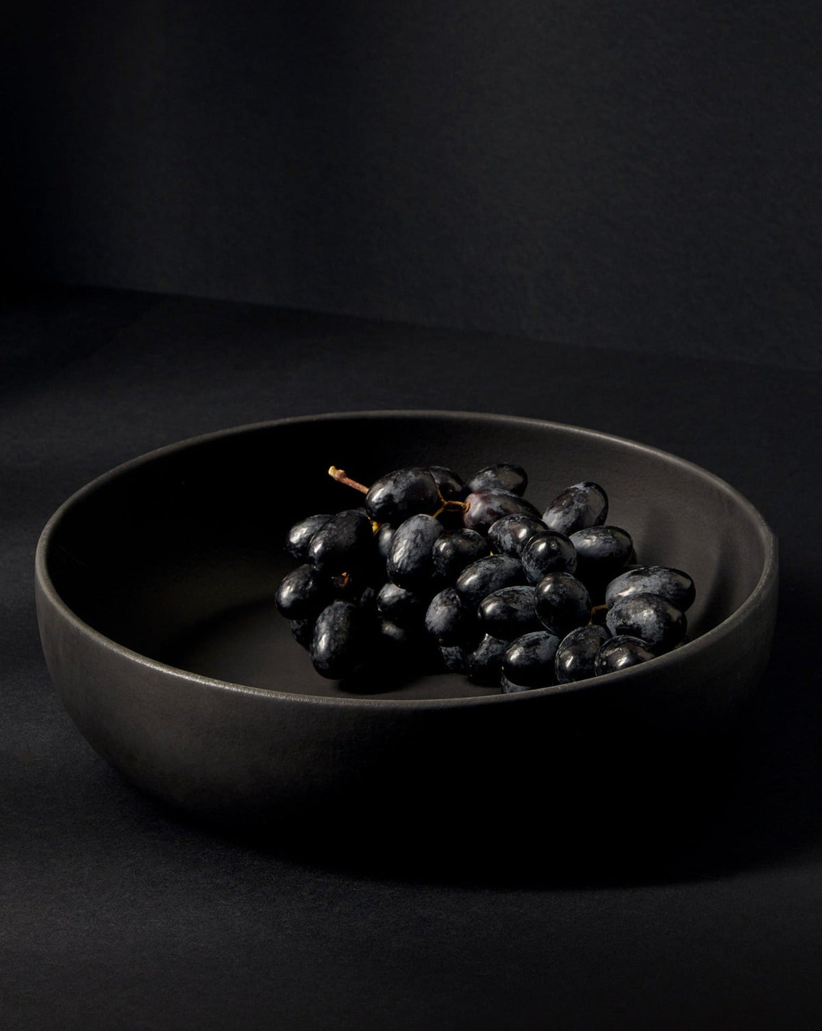 A beige Stoneware Shallow Serving Bowl with a capacity of 60 oz, displayed against a neutral background with a small amount of food items like pasta or noodles in it to showcase its size and shape.