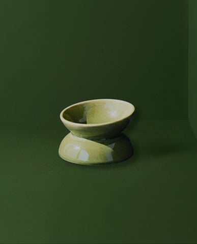 Green ceramic bowl on a dark green background