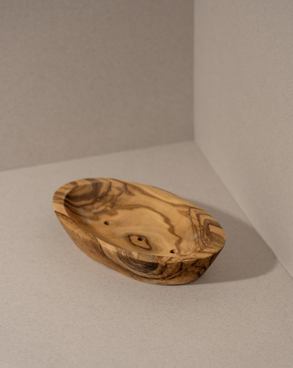 A rectangular natural olive wood soap holder with visible wood grain and draining holes.