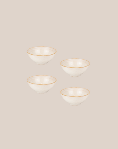 Four small white ceramic bowls with thin ivory rims, arranged in a loose grid on a solid light beige background.